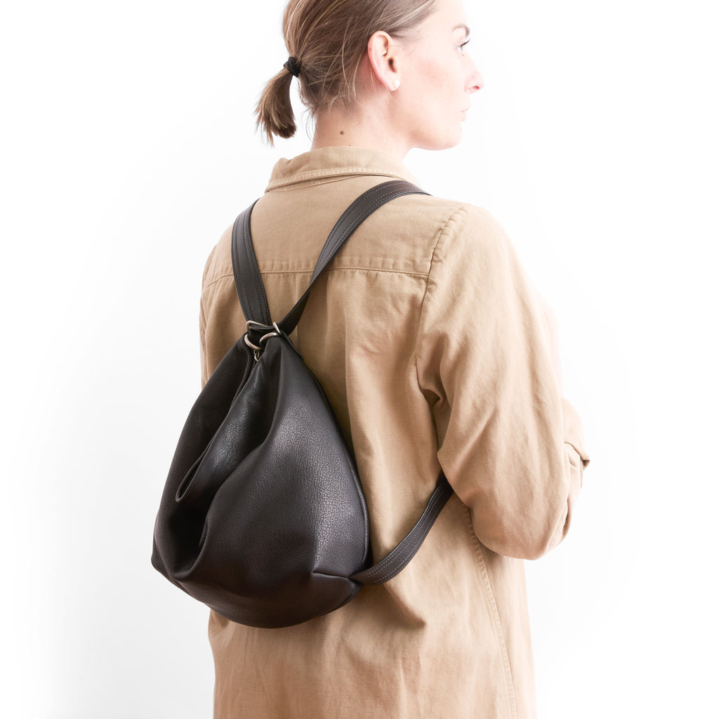 model with duffel medium in nero and black strap configured as backpack rear three-quarter view