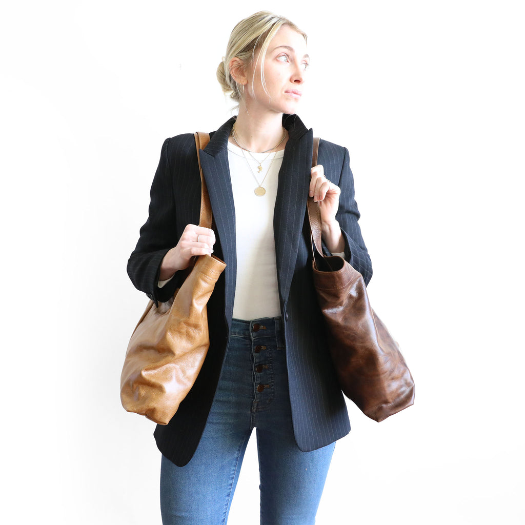 model holding two scarborough totes in light saddle (left) and rustic pecan (right)