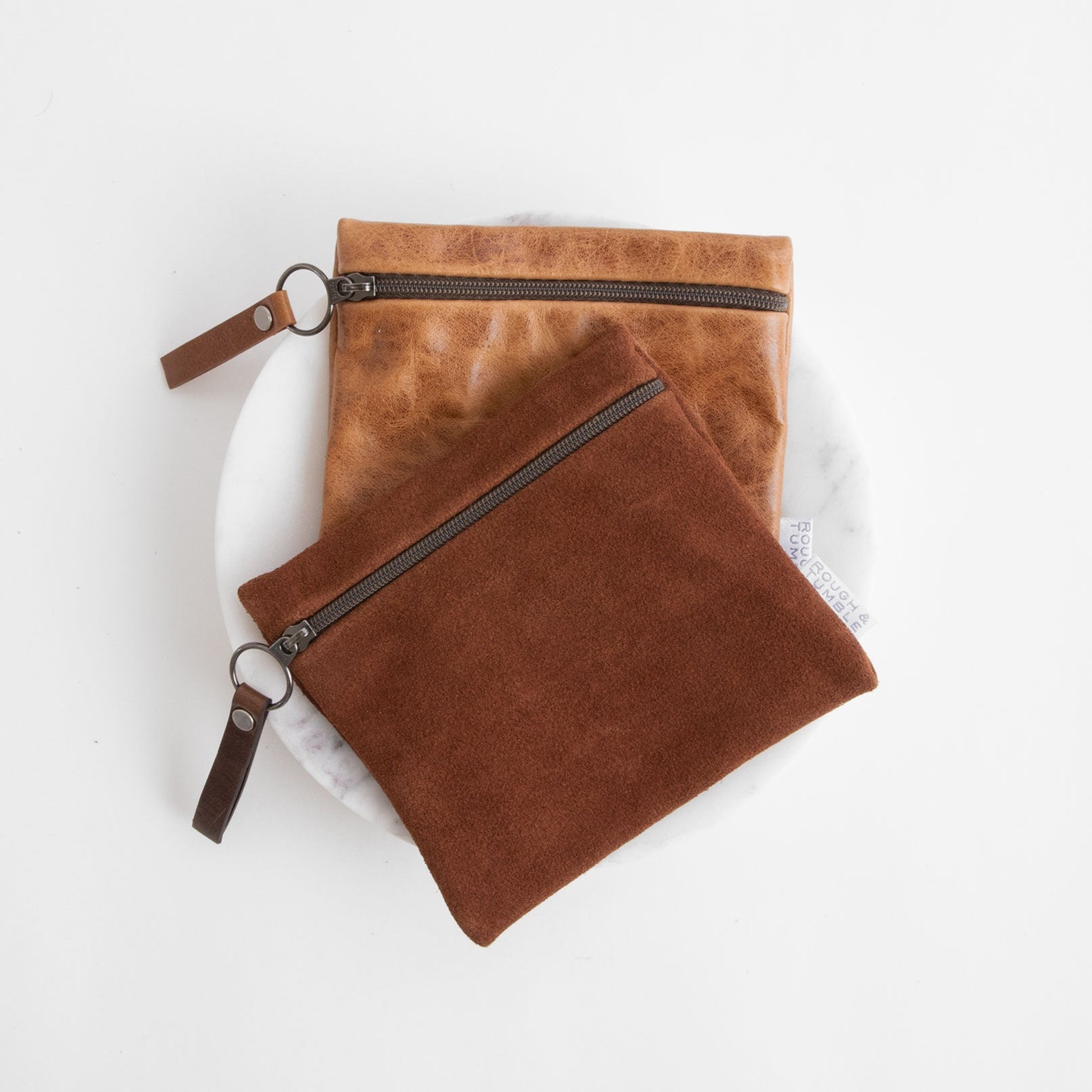 card case in tawny suede laying on top of a card case in light saddle